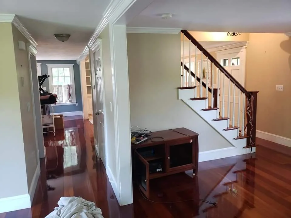 Before: Entryway between dining and living room with beige walls and the side view of the staircase. The room is unpainted. Flagler County Painter, Residential Painting, Entryway Transformation, T&B Paint Pros LLC.