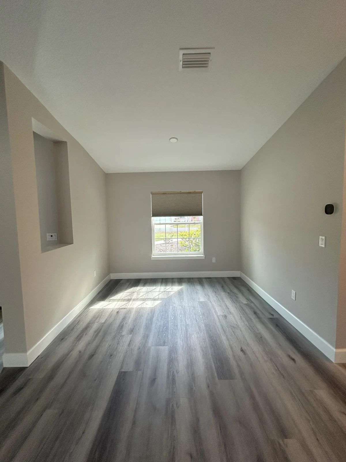 Straight-on view of the freshly painted dining nook in Palm Coast, FL, featuring Sherwin Williams Popular Gray walls, white trim, a large window overlooking the pool deck, and a built-in buffet cabinet with granite countertops.