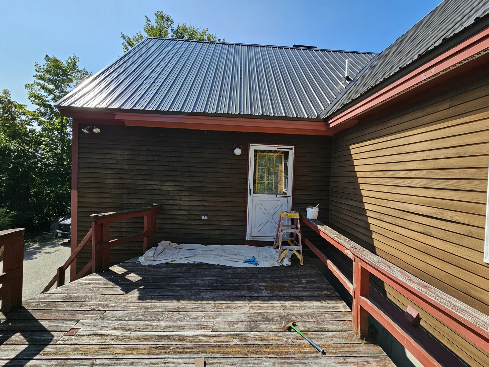 Final stages of exterior painting on a dark brown and red-trimmed home in Harvey, NH. Expertly painted by T&B Paint Pros. tbpaintpros Flagler County Florida experienced painter, specializing in high-quality, weather-resistant home exteriors.