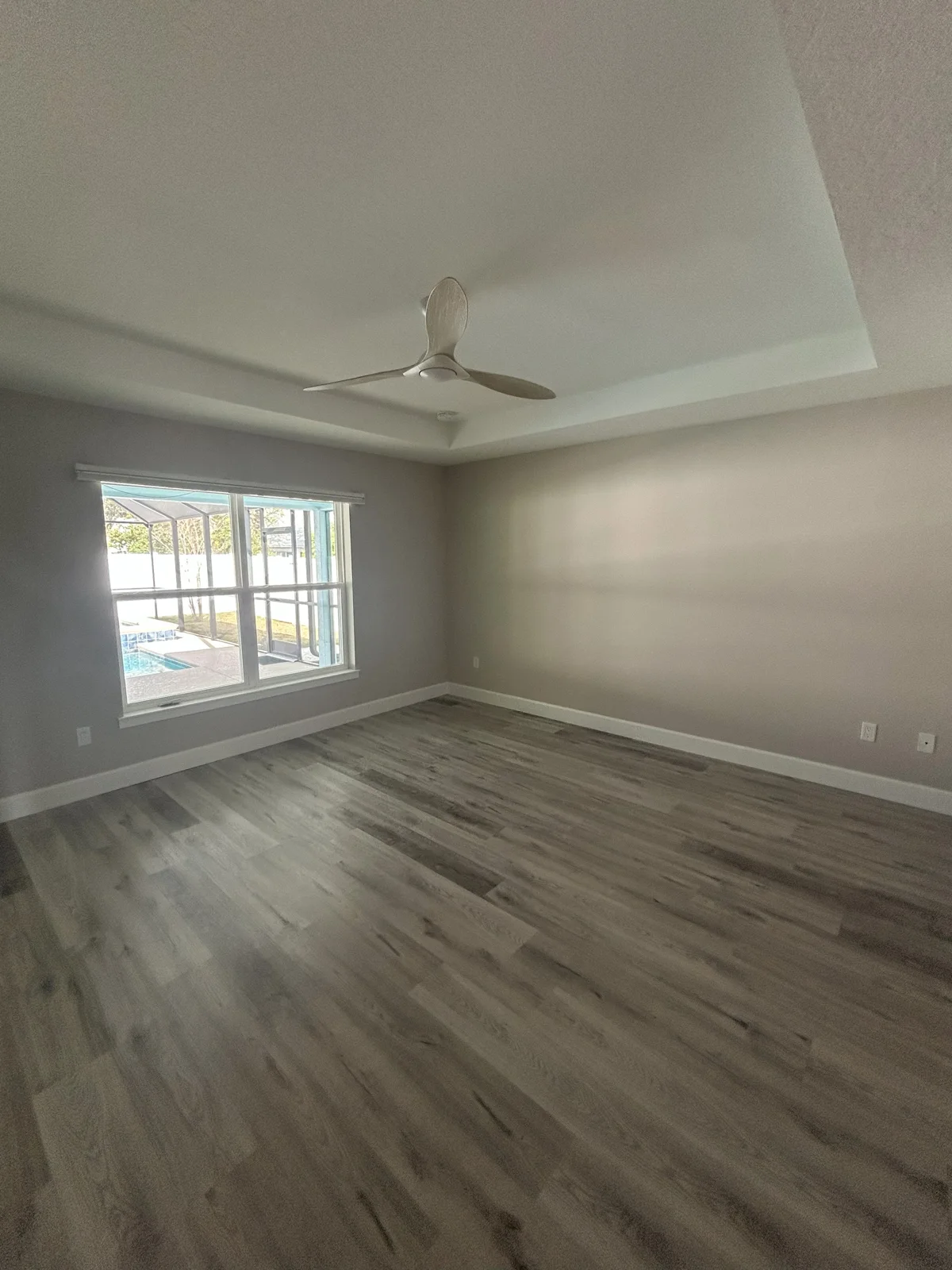 T&B Paint Pros LLC - Primary Bedroom entry view in Palm Coast FL with walls painted in Sherwin Williams Popular Gray and white trim. High tray ceilings enhance the airy and modern feel.