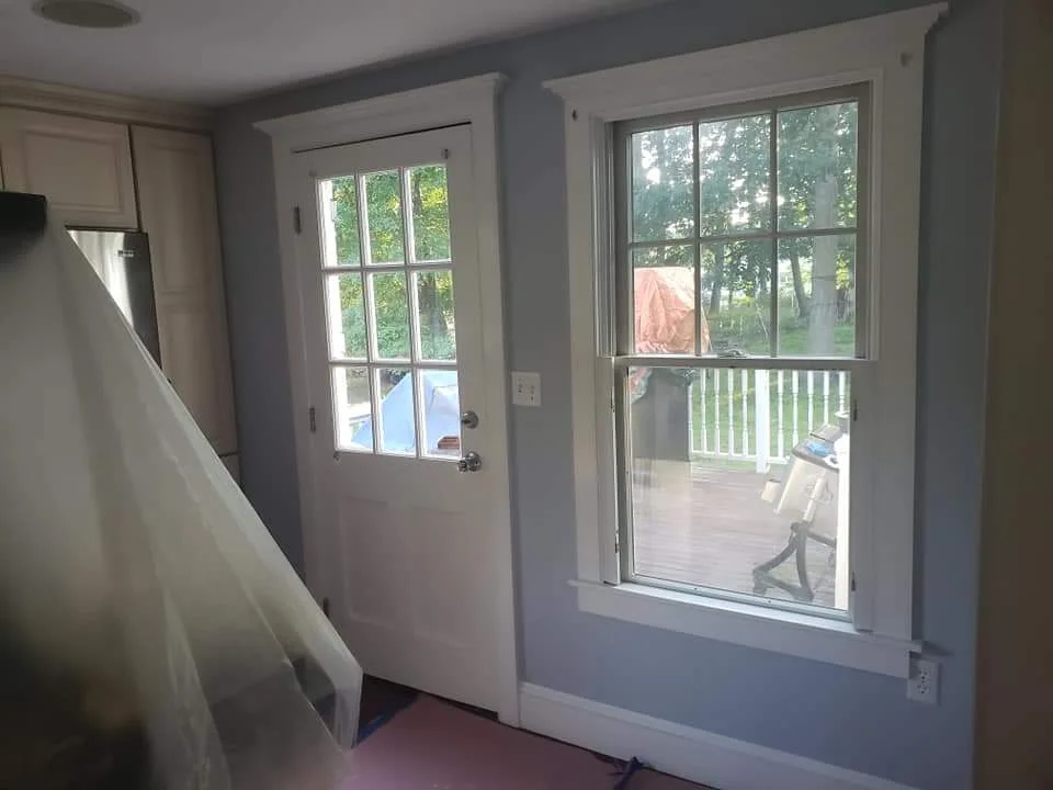 T&B Paint Pros LLC kitchen and living room repaint, featuring soft blue wall color around door and window. Attention to detail with floor protection during the painting process. Flagler County painting company, kitchen and living room makeover, interior painting.