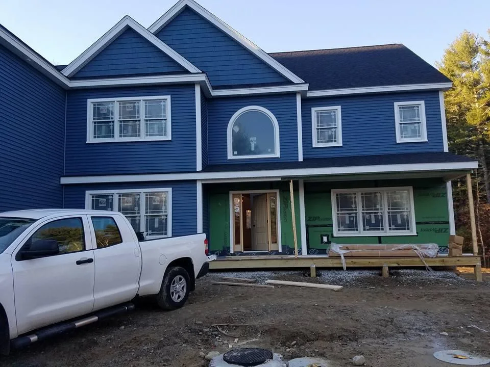 Freshly painted colonial-style home in New England with blue clapboard siding and a covered deck, painted by T&B Paint Pros.