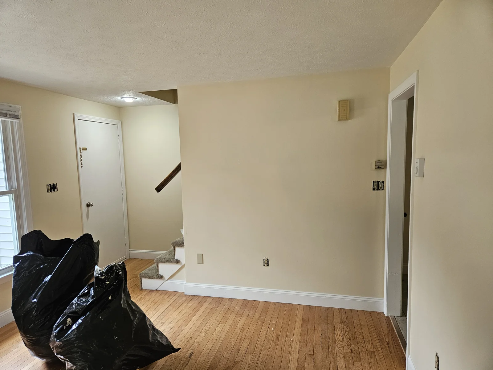 Living room with freshly painted walls, showing the cleaned-up space and completed painting job by T&B Paint Pros. Contractor bags and cleanup materials visible. Flagler County Painter, Living Room Repaint.
