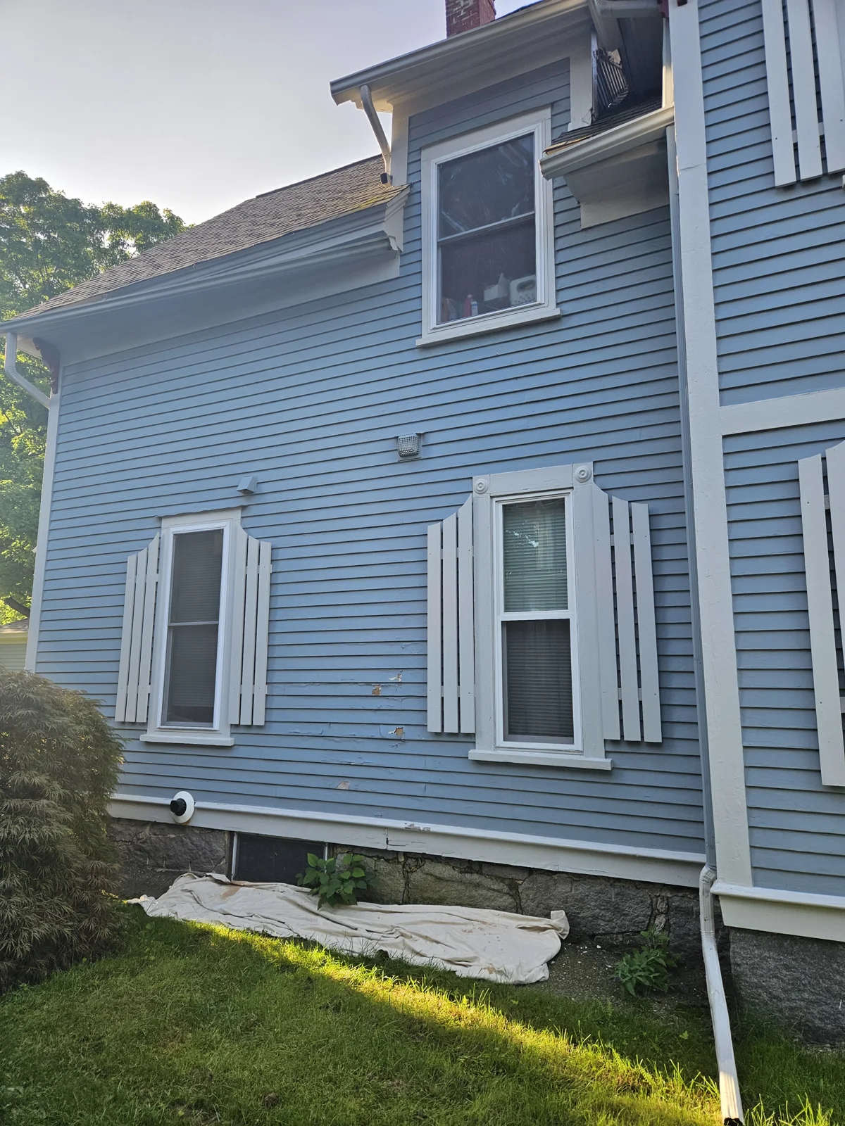 Before exterior siding repair and repaint—chipping paint and siding damage on a soft blue home with white trim. T&B Paint Pros prepares for expert restoration. tbpaintpros Flagler County Florida experienced painter for professional home painting and siding repair.