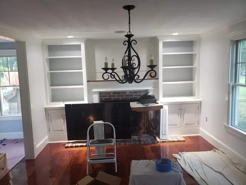 T&B Paint Pros LLC Interior painting after photo, living room, kitchen, fireplace built-ins, freshly painted vibrant white walls, soft blue kitchen wall. This after photo shows the complete transformation of the living room and kitchen, featuring newly painted white built-ins and kitchen wall in soft blue. Flagler County Painter, Painting Company, tbpaintprosllc