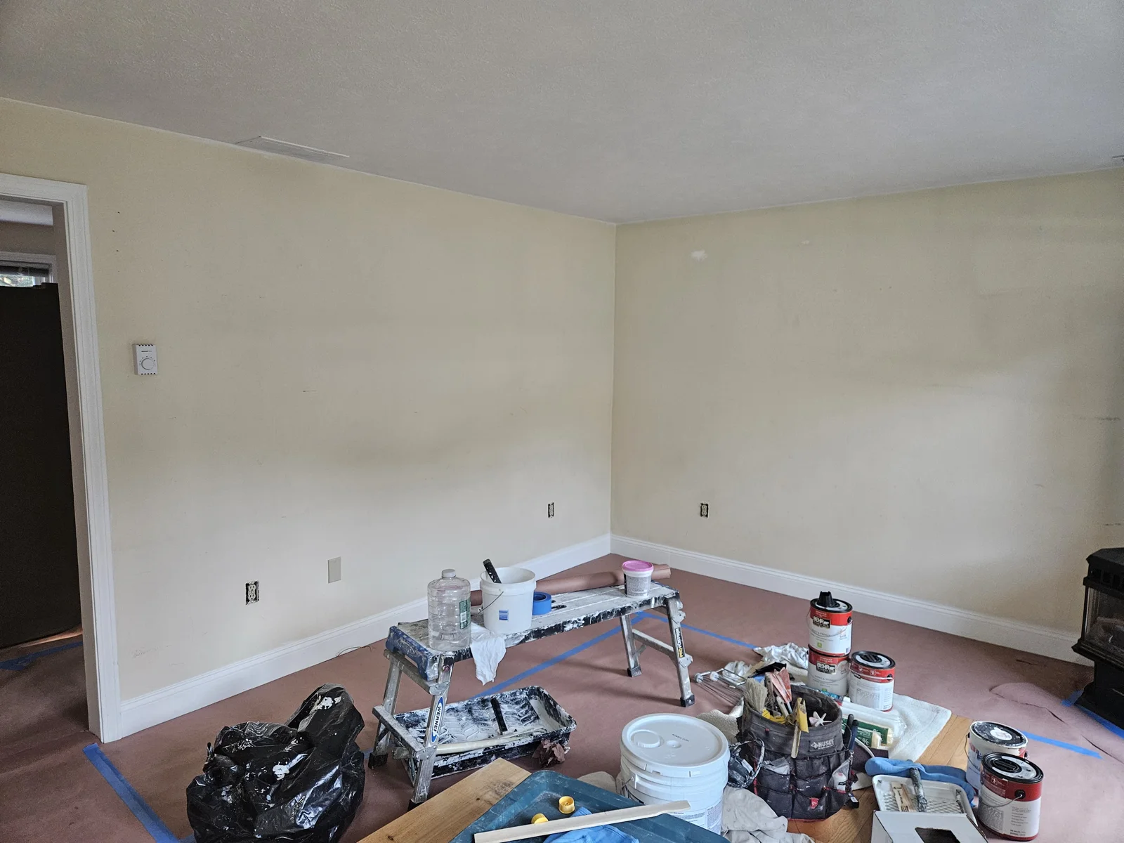 Living room with yellow walls, floors covered, and prep work in progress for repaint. Flagler County Painter, Living Room Repaint, T&B Paint Pros LLC.