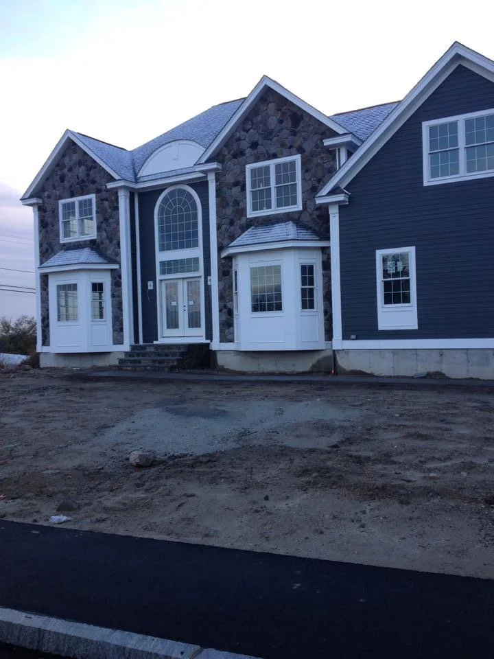 Beautifully painted two-story home in Walpole, MA, featuring dark blue siding with white trim, expertly painted by T&B Paint Pros to enhance its exterior beauty and durability. tbpaintpros Flagler County Florida expert painters