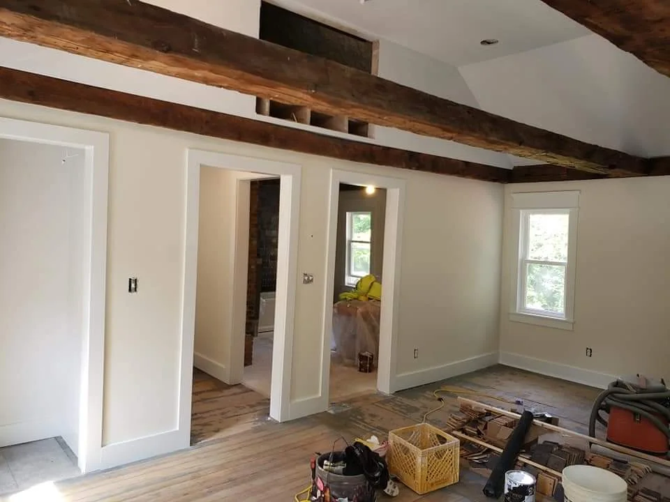 T&B Paint Pros LLC living area with vaulted ceilings, white walls, and historical post-and-beam structure. Elegant home transformation with a focus on architectural details. Flagler County painter, historical home renovation, interior painting.