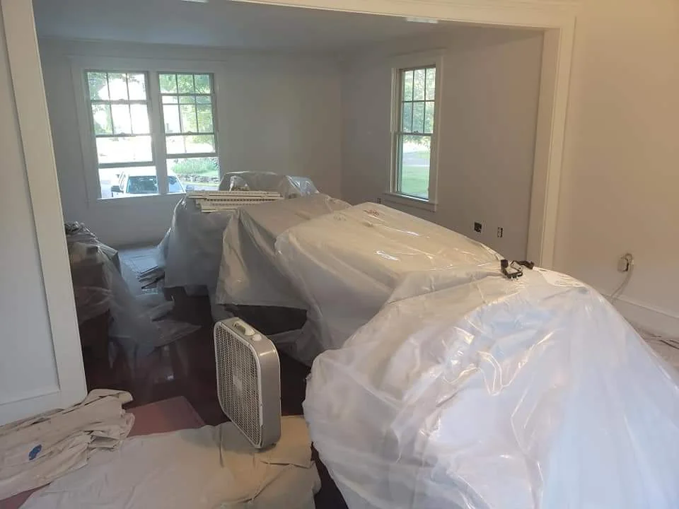 T&B Paint Pros LLC living room with valuables covered, rosin paper on hardwood floors, white walls and trim, interior painting Flagler County.
