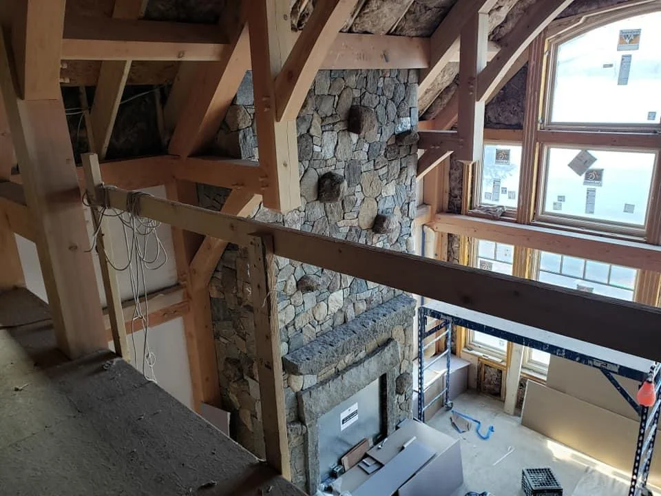 Post and Beam home with a custom stone fireplace with plaster walls.